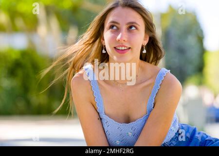 Primo piano di ragazza Teenage sorridente seduta e Pendente verso la Camera su gradini concreti di Palo Alto City Hall Plaza Foto Stock