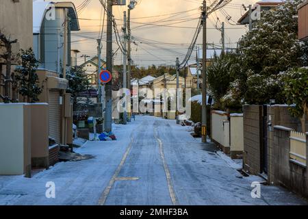 Pneumatici in neve leggera su strada in un tranquillo quartiere suburbano all'alba Foto Stock