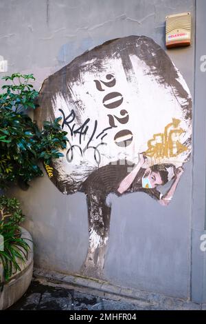 Un poster di carta, raffigurante un giovane uomo con una maschera, trasportando un sacco enorme che dice 2020. È un simbolo, metafora della pandemia di Covid. Un esempio di g Foto Stock