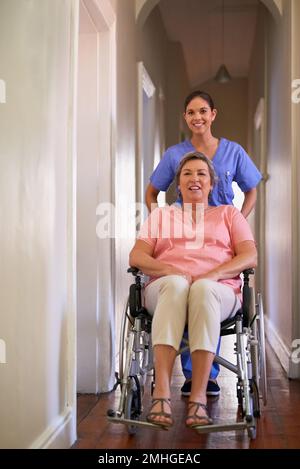 Muoversi con un po 'di supporto. un operatore sanitario che spinge un paziente anziano su una sedia a rotelle in una casa di cura. Foto Stock