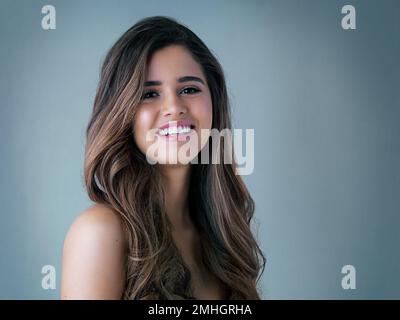 Youre mai completamente vestito senza i capelli grandi. Foto studio di una bella giovane donna che posa su uno sfondo grigio. Foto Stock