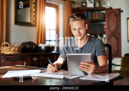 Tutto ciò di cui avete bisogno sono le risorse giuste. un giovane uomo che usa un tablet digitale mentre lavora a un progetto a casa. Foto Stock