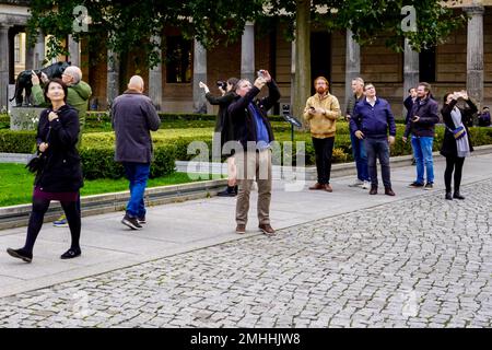 Gruppo di turisti stupiti che scattano foto nel cortile del colonnato di fronte alla Vecchia Galleria Nazionale sull'Isola dei Musei di Berlino. Foto Stock