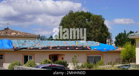 Tetto residenziale in disperata necessità di riparazione tegole Sostituzione con teloni di protezione dopo danni grandine temporale Foto Stock