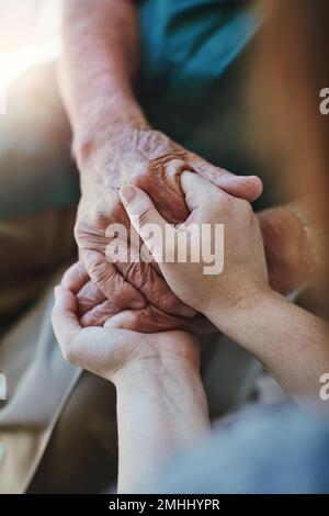 Faccia il tempo per essere gentile. Primo piano di una donna che tiene le mani di un uomo anziano in comodità. Foto Stock