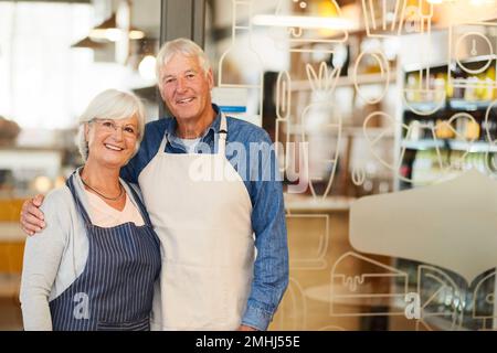 Coniugi, amici e partner commerciali. Ritratto di due proprietari di affari anziani felici che si pongono insieme all'interno della loro caffetteria. Foto Stock