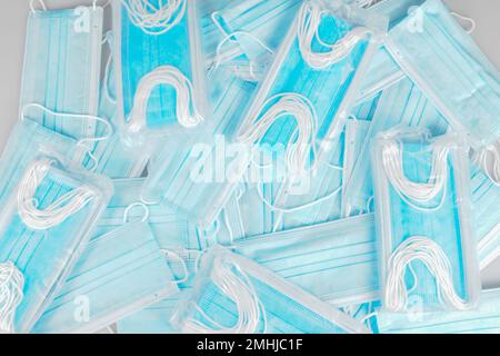Stack di maschere facciali blu su sfondo in concetto pandemico Foto Stock