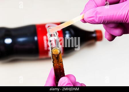 Mosca, Russia - 12 gennaio 2023: Misurazione del livello di pH della Coca Cola Classic, l'indicatore rosa mostra l'acidità. La Coca-Cola (Coca-Cola) è morbida carbonata Foto Stock