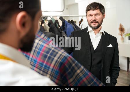 Esperto su misura e il suo cliente che sceglie il materiale per vestito Foto Stock