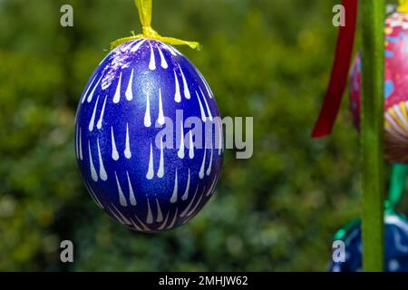 Le uova dipinte pendono dai rami dell'albero di Pasqua. Il fuoco è su un uovo giallo dipinto dai bambini a mano. Foto di alta qualità Foto Stock