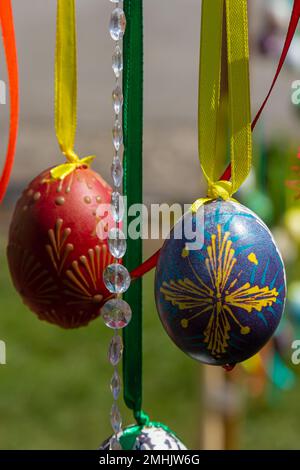 Le uova dipinte pendono dai rami dell'albero di Pasqua. Il fuoco è su un uovo giallo dipinto dai bambini a mano. Foto di alta qualità Foto Stock