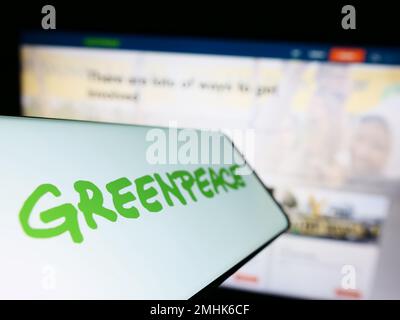 Telefono cellulare con logo di campagna ambientale rete Greenpeace sullo schermo di fronte al sito web. Messa a fuoco a sinistra del display del telefono. Foto Stock