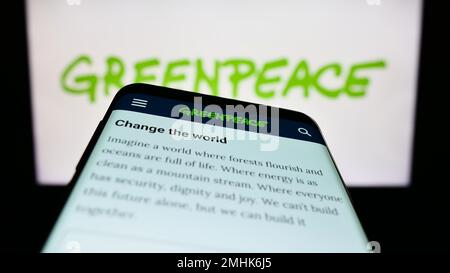 Smartphone con sito web di campagna ambientale rete Greenpeace sullo schermo di fronte al logo. Messa a fuoco in alto a sinistra del display del telefono. Foto Stock