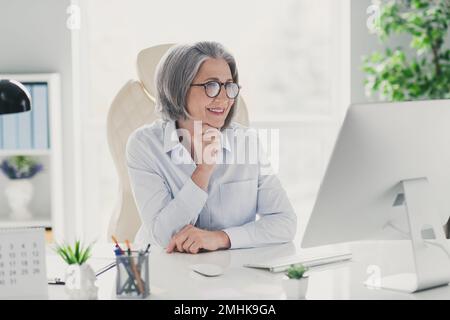 Ritratto fotografico di vecchia donna matura manager esperto start up seduta bianco boss sedia moderno interno ufficio lettura e-mail Foto Stock