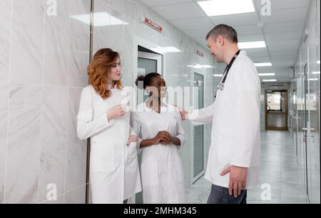 un gruppo di medici ospedalieri comunica tra loro nel corridoio della clinica. Foto Stock