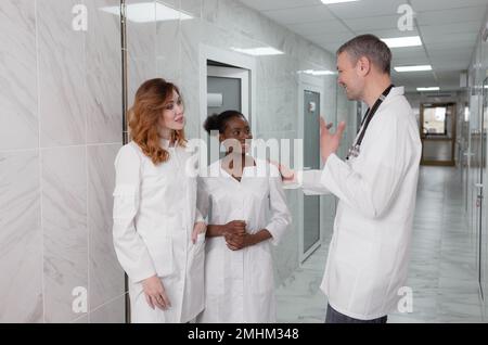 un gruppo di medici ospedalieri comunica tra loro nel corridoio della clinica. Foto Stock
