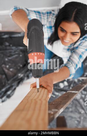 Focalizzazione selettiva sulla perforazione con una giovane donna indiana si concentra sul tiro in testa al legno Foto Stock
