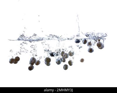 Mirtilli che affondano in acqua con bolle d'aria sfondo bianco. Foto Stock