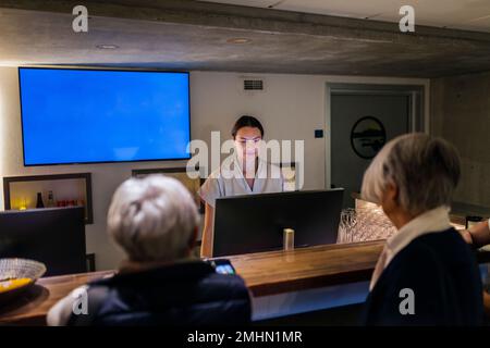 Addetto alla reception che assiste il cliente presso il centro benessere Foto Stock