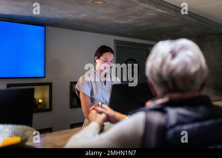 Addetto alla reception che assiste il cliente presso il centro benessere Foto Stock