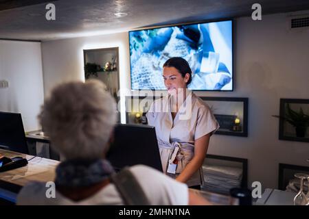 Addetto alla reception che assiste il cliente presso il centro benessere Foto Stock