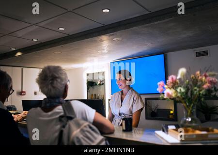 Addetto alla reception che assiste il cliente presso il centro benessere Foto Stock