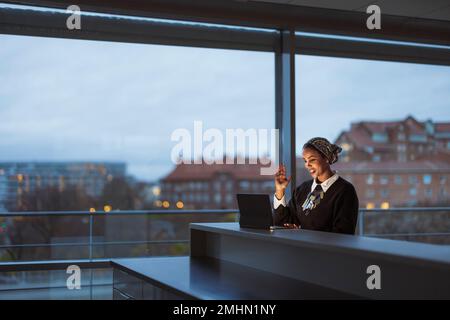 Giovane donna sorridente che videochiama sul laptop Foto Stock
