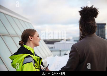 Gli architetti parlano mentre tengono progetti Foto Stock