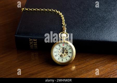 Orologio da tasca vintage e catena con una bibbia cristiana su una superficie di legno lucido Foto Stock