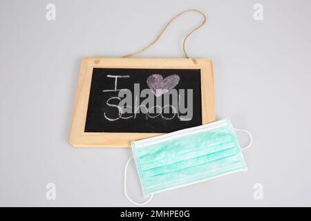 amo il testo della scuola su lavagna ardesia con la maschera di covid del virus pandemico su sfondo grigio Foto Stock