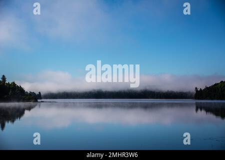 lago con nuvole riflesse e colline boscose nel Parco Algonquin Foto Stock