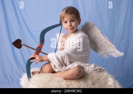 Piccolo toddle cupido ragazzo, tenere arco e freccia, bel cherubino biondo, amore Foto Stock