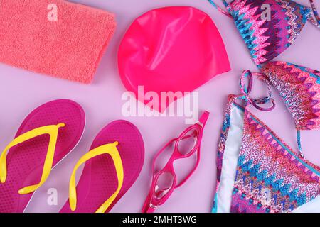 Composizione piana con accessori per il nuoto su fondo viola Foto Stock