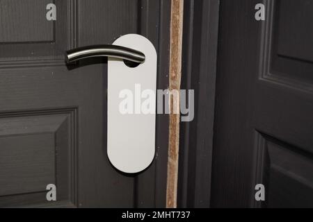 Gancio porta bianco su porta classica grigia con etichetta vuota non disturbare reale Foto Stock