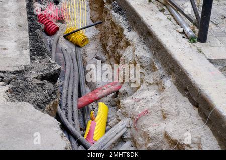 cavi sotterranei durante i lavori di gas elettrico e telecomunicazioni cavi e tubi dell'acqua sulla strada Foto Stock