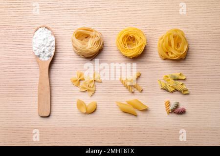 Composizione di posa piatta con diversi tipi di pasta su tavola di legno Foto Stock