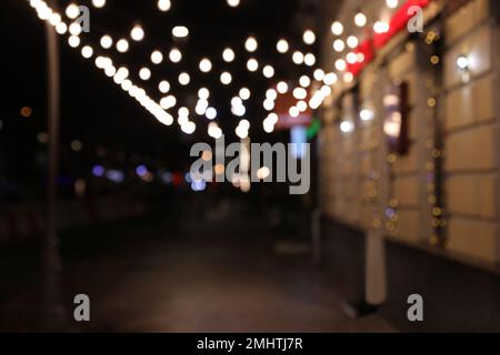 Splendida vista sulla strada notturna della città decorata con ghirlande. Effetto bokeh Foto Stock