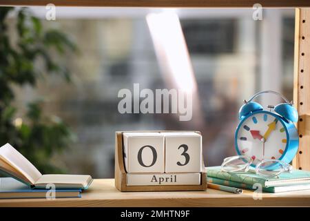 Calendario a blocchi in legno e sveglia su scaffale interno Foto Stock