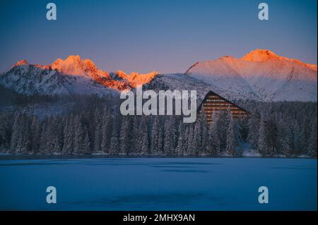 La bellezza mozzafiato di un'alba invernale negli alti Tatra, vista dalla superficie ghiacciata del lago Strbske pleso. Foto Stock