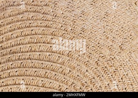 Sfondo texture di un cappello o borsa di paglia, primo piano tonalità giallo sabbia chiaro. Accessori estivi o sfondi. Foto Stock