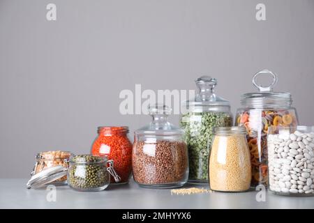 Vasetti con cereali diversi su tavola grigia Foto Stock