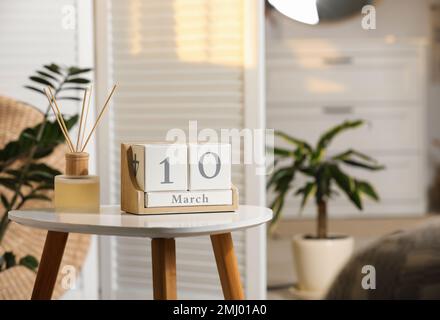 Calendario a blocchi in legno e profumatore d'aria a canna aromatica su tavolo bianco all'interno. Spazio per il testo Foto Stock