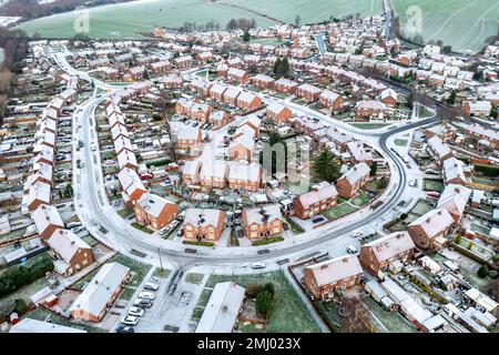 Vista aerea sopra le strade coperte di neve e i tetti di uno sviluppo residenziale suburbano con i proprietari di case che lottano per permettersi le bollette di energia durante Foto Stock
