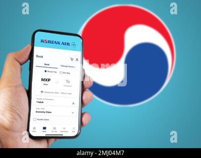 Seoul, KR, gennaio 2023: Mano che tiene un telefono con richiesta di prenotazione di voli Korean Airlines. Logo Korean Airlines sfocato su sfondo azzurro. Bo Foto Stock