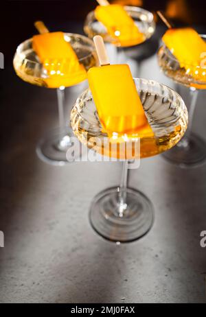 Quattro bicchieri di champagne e gelato all'arancia. Elegante cocktail alcolico sul tavolo leggero in morbido sole rayson. Concetto di bevande deliziose. Foto Stock
