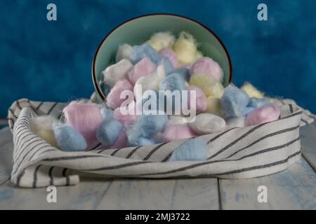 Palline di cotone colorate in vari contenitori su sfondo blu Foto Stock