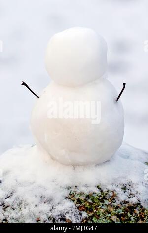 Primo piano di un pupazzo di neve piccolo ma perfettamente formato, costruito sulla sommità di un palo di cemento con bastoni per le braccia, ma senza caratteristiche facciali. Foto Stock