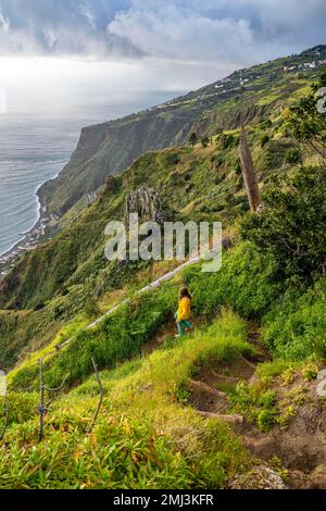 Escursionista sul sentiero, Miradouro da Raposeira, scogliere, costa e mare, Paul do Mar, Madeira, Portogallo Foto Stock