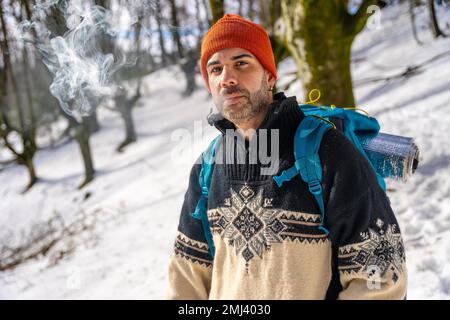 Ritratto di un uomo che fuma una sigaretta su una collina innevata in inverno Foto Stock