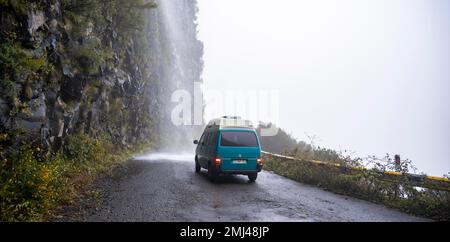 Cascata dos Anjos, autobus VW conduce attraverso una cascata sulla strada, Madeira, Portogallo Foto Stock